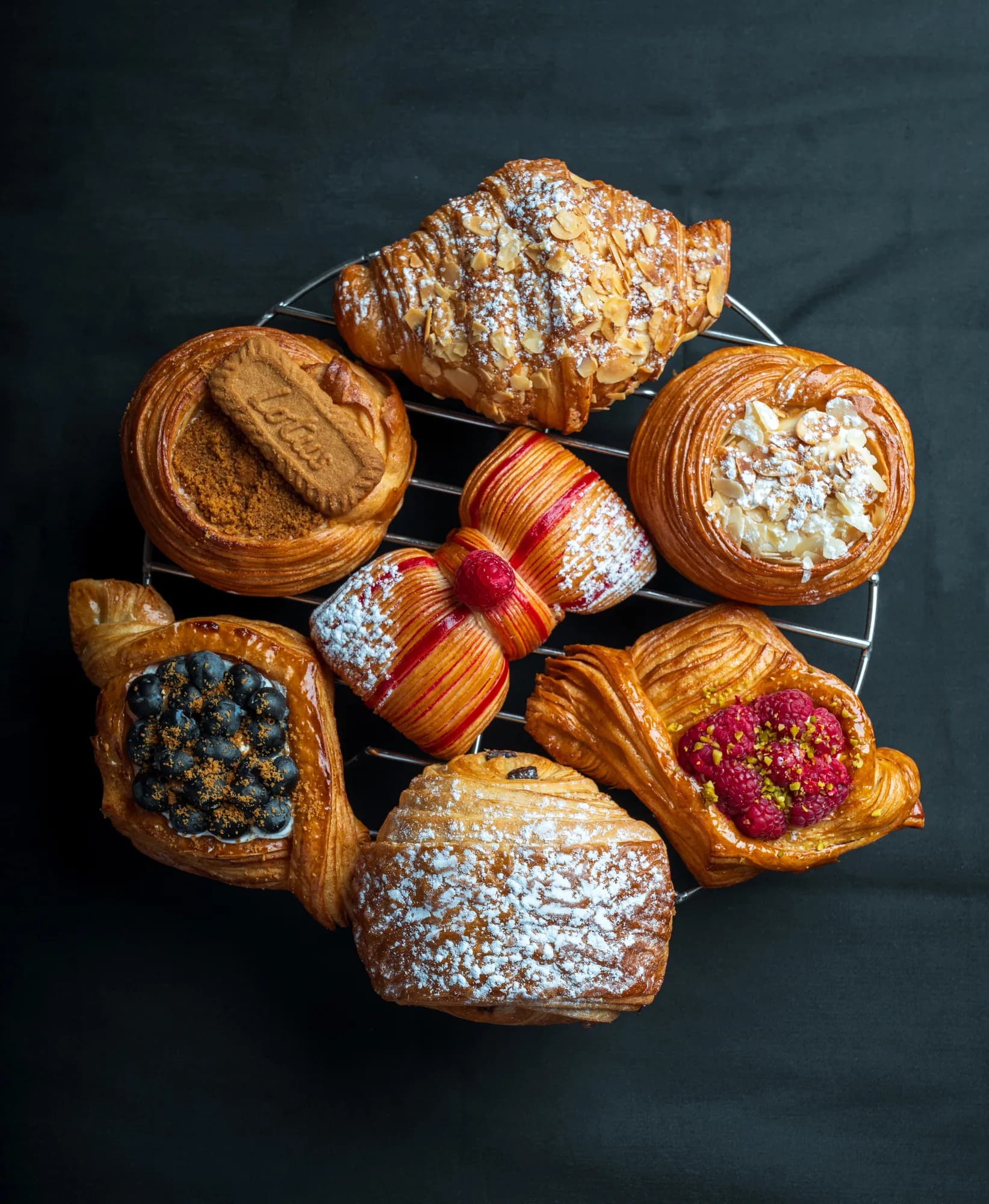 A Daar baker holding an almond croissant