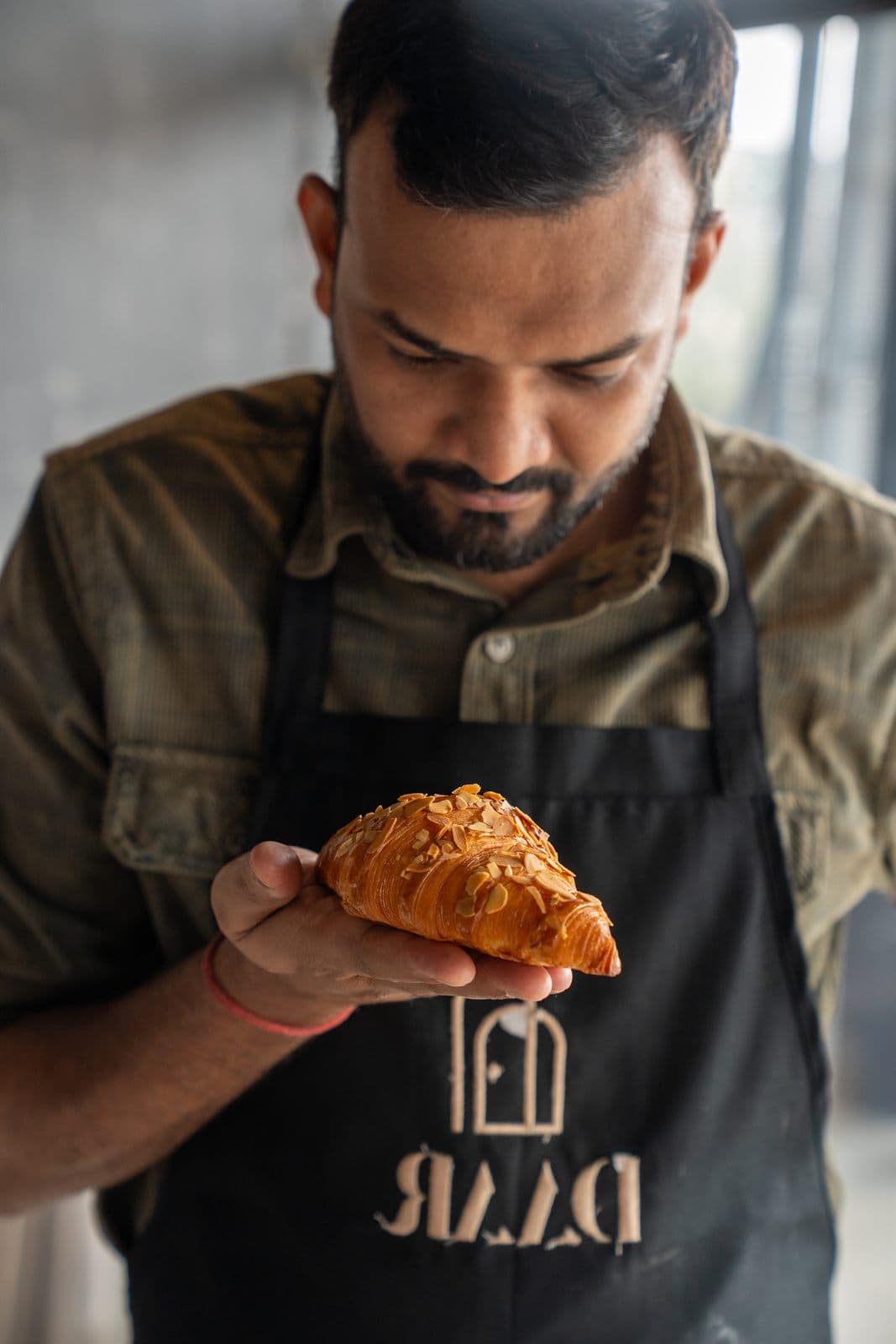 A baker at Daar holding an almond croissant